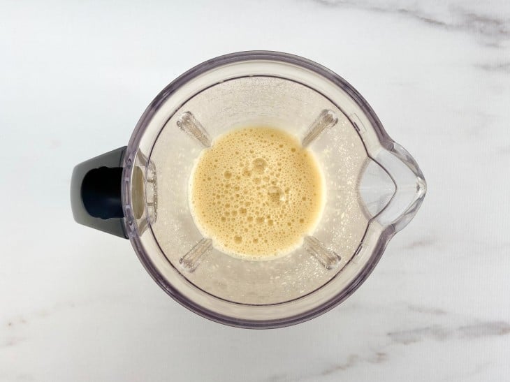 Um liquidificador com a mistura da laranja, ovos, açúcar demerara e essência de baunilha.