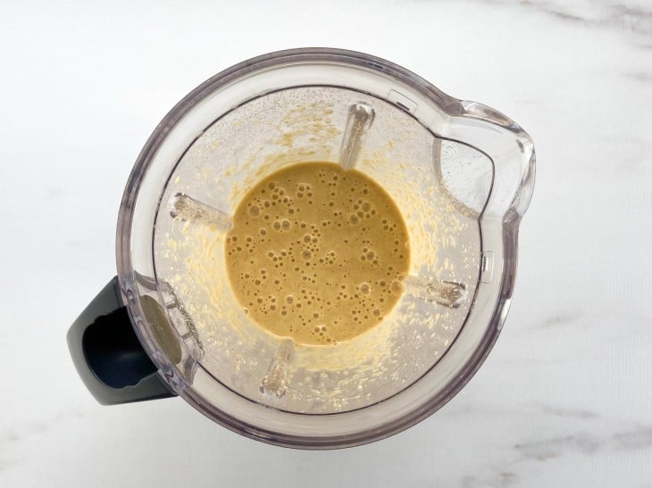 Um liquidificador com a mistura da laranja, ovos, açúcar demerara, farinha de aveia e essência de baunilha.