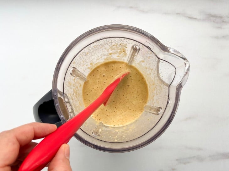 Um liquidificador com a mistura da laranja, ovos, açúcar demerara, farinha de aveia, fermento e essência de baunilha.