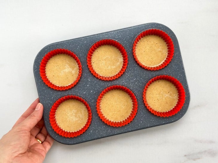 Várias forminhas de cupcake com a massa crua do muffin.