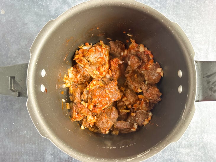 Extrato de tomate, páprica e cebola sendo incorporados à carne.