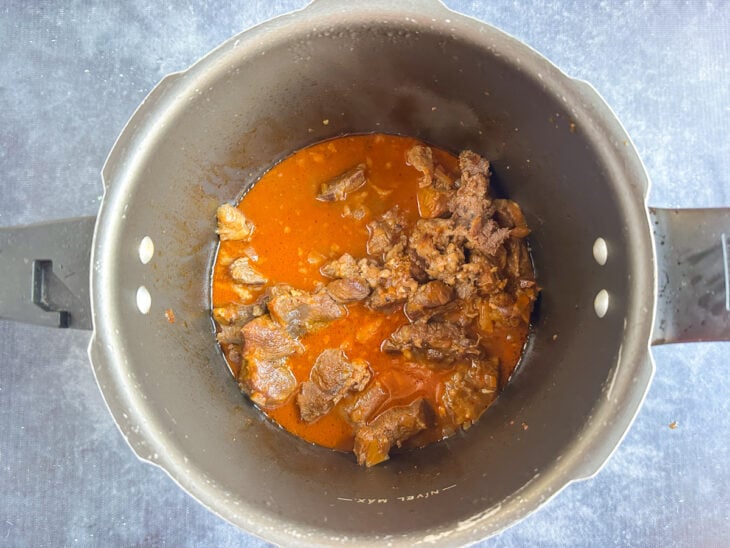 Carne cozinhando na pressão com caldo temperado na panela.
