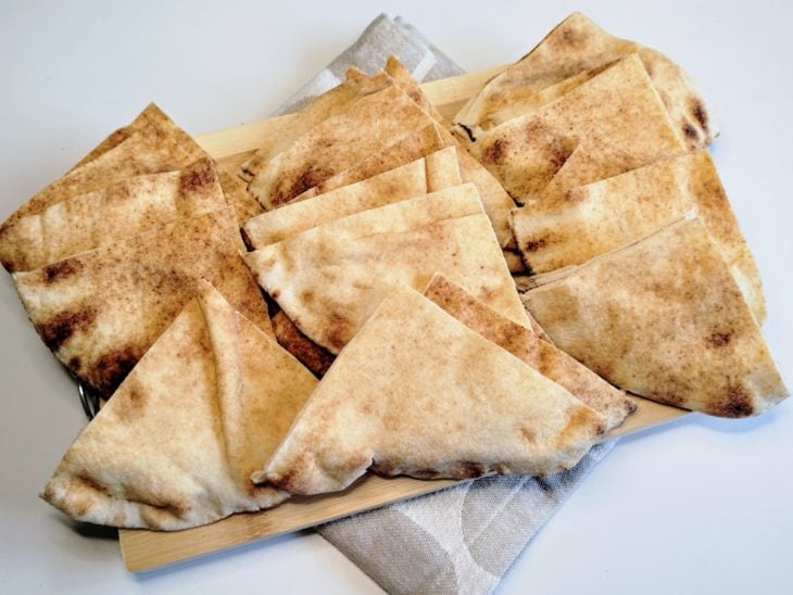 Uma tábua com pão árabe fatiado.