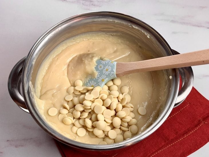 Uma panela contendo um creme branco com chocolate branco.