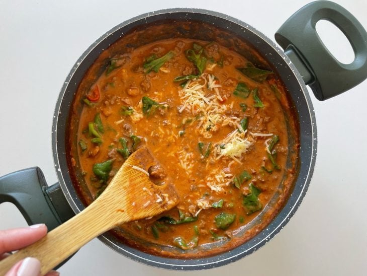 Espinafre, manjericão e parmesão adicionados na panela.
