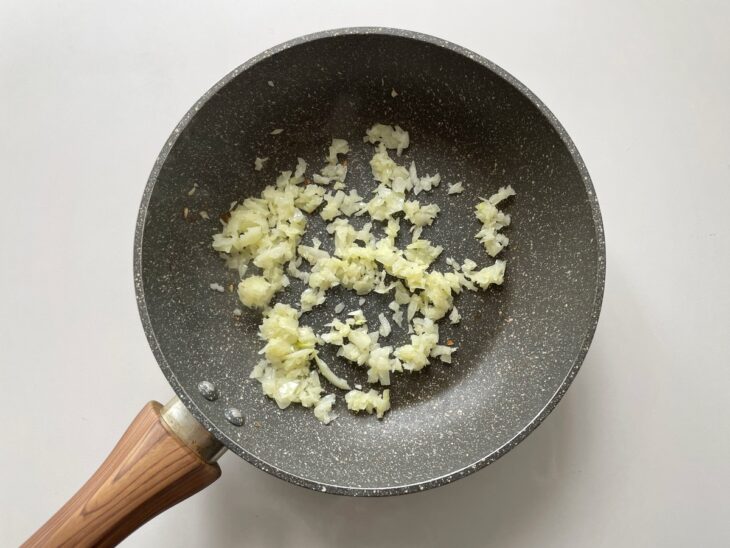 Cebola picada sendo refogada na manteiga derretida dentro da panela.
