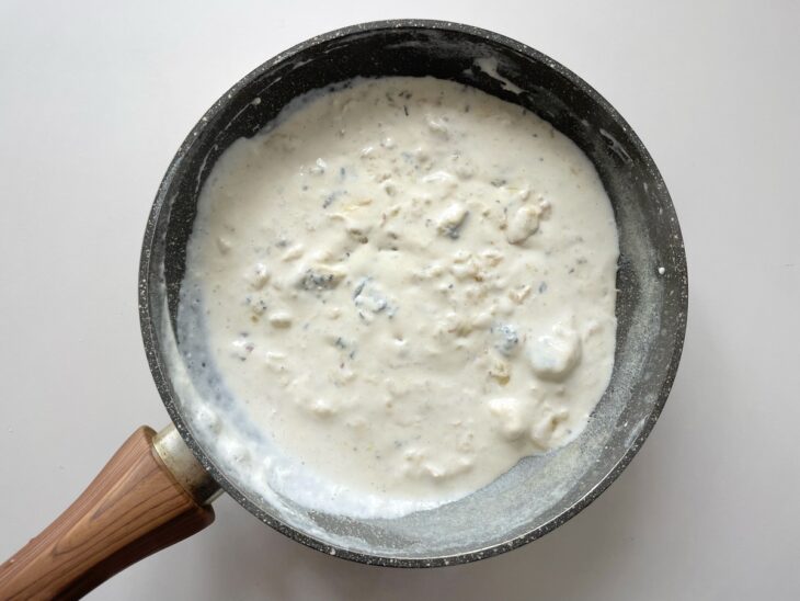 Creme de leite fresco e queijos ralados misturados ao molho na panela.