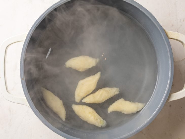 Nhoques colocados em uma panela com água fervente.