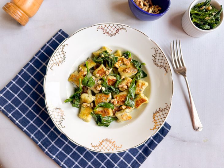 Nhoques prontos, servidos em prato, garfo ao lado.