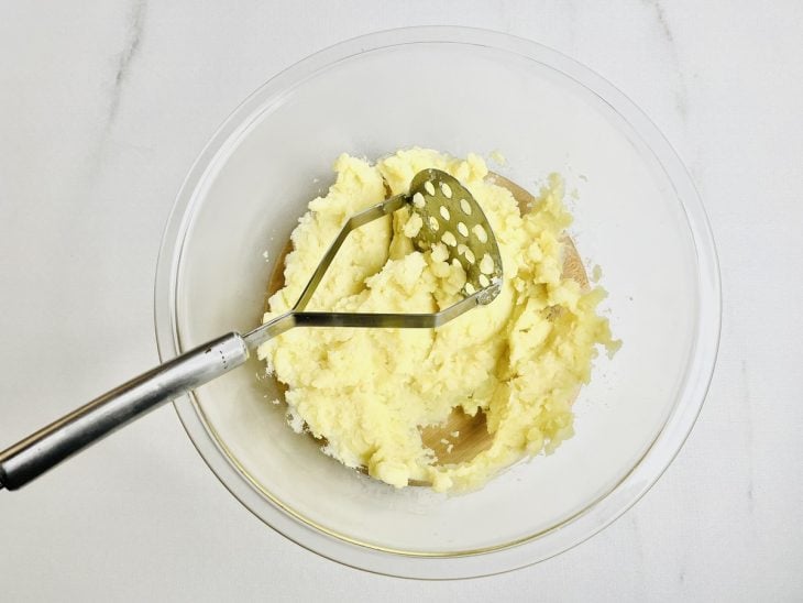 Batatas cozidas amassadas em uma tigela de vidro.
