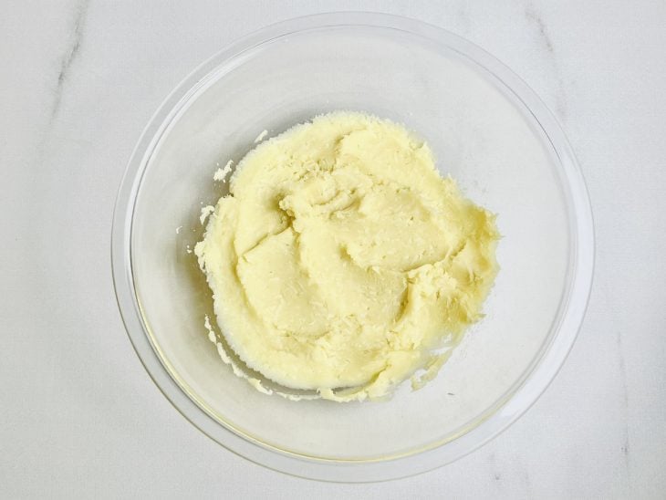 Parmesão, sal, pimenta e noz-moscada adicionados a tigela com purê.
