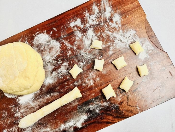 Massa sendo cortada sobre uma tábua de cozinha enfarinhada.