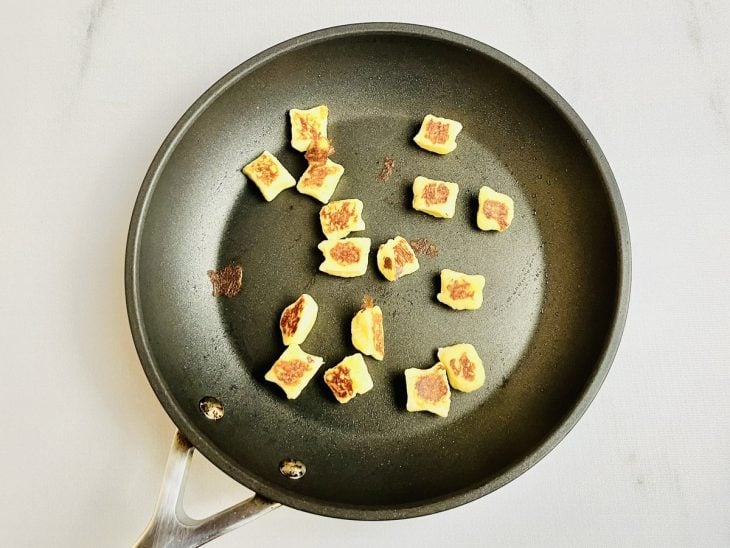 Nhoques fritos em uma frigideira com azeite.