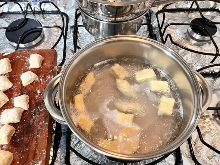 Uma panela com água fervente e os nhoques cozinhando.