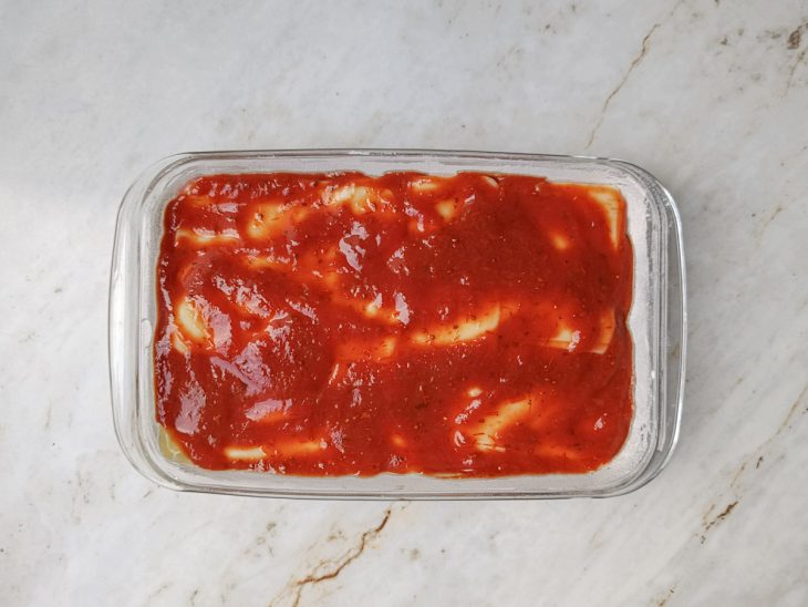 Refratário com camada final de molho de tomate.
