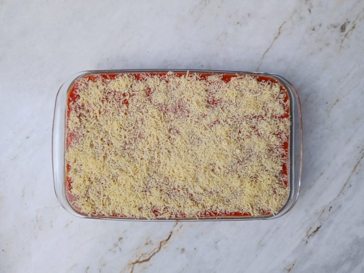 Refratário com camada final de queijo parmesão ralado.