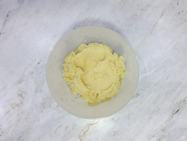 Mandioca amassada formando um purê liso e uniforme.