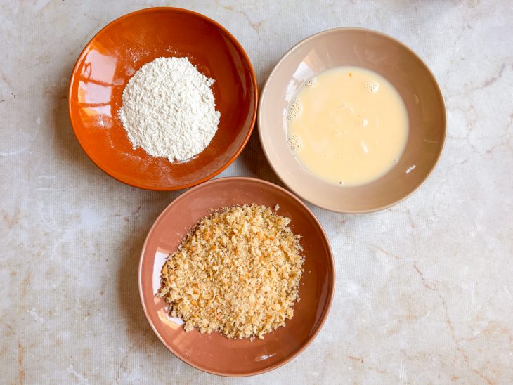 Farinha de trigo, a farinha de rosca e os ovos batidos com o leite em tigelas separadas.