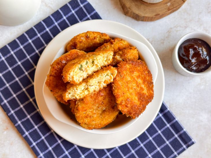 Nuggets prontos, servidos em tigela acompanhados de molho.