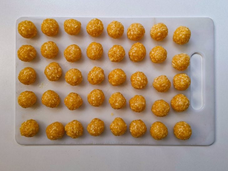 Bolinhas de doce sendo modeladas com as mãos untadas.