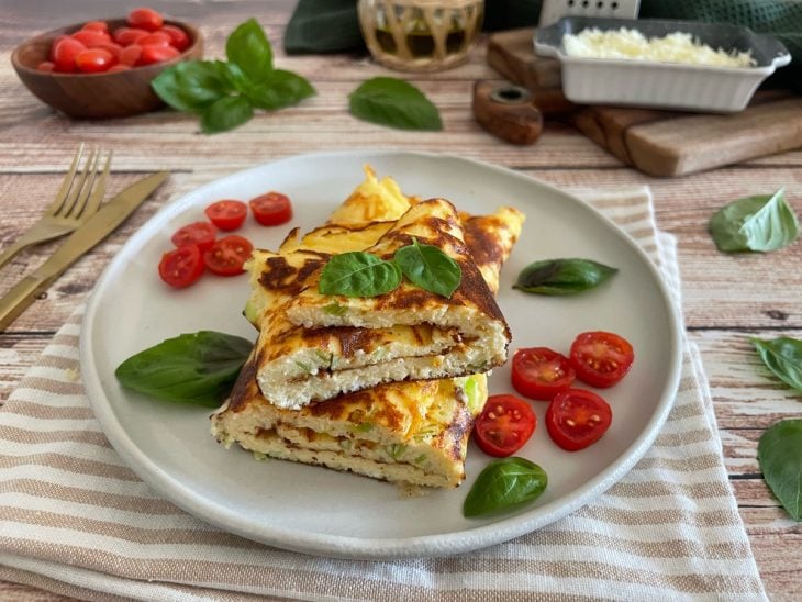 Omelete pronta, decorada com tomates-cereja e manjericão.