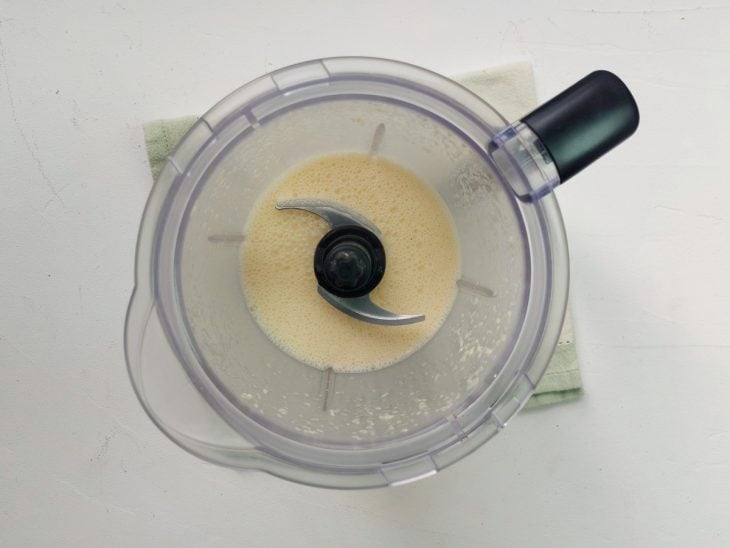 Um processador com a mistura de ovos, cebola, alho, queijo, sal e pimenta-do-reino.