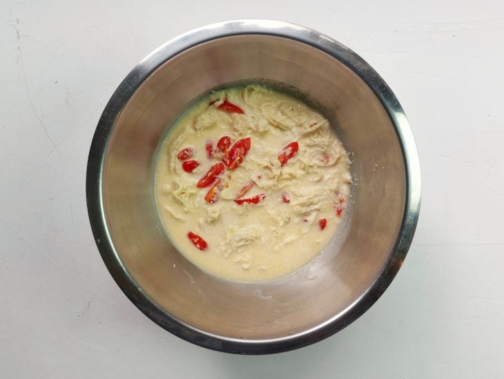Um recipiente contendo a mistura de ovos, cebola, alho, queijo, sal, pimenta-do-reino, frango desfiado e tomates picados.