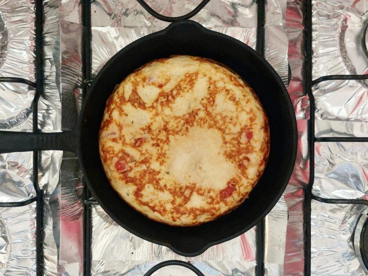 Uma frigideira contendo omelete de frango com tomate.