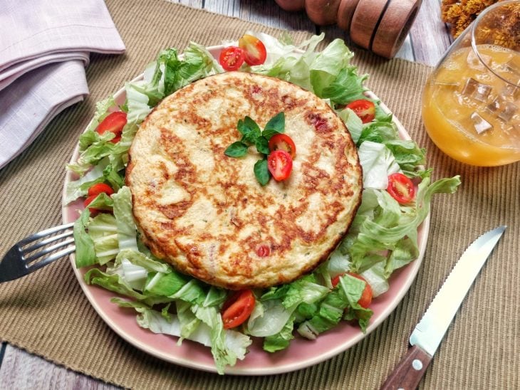 Um recipiente contendo omelete de frango com tomate.