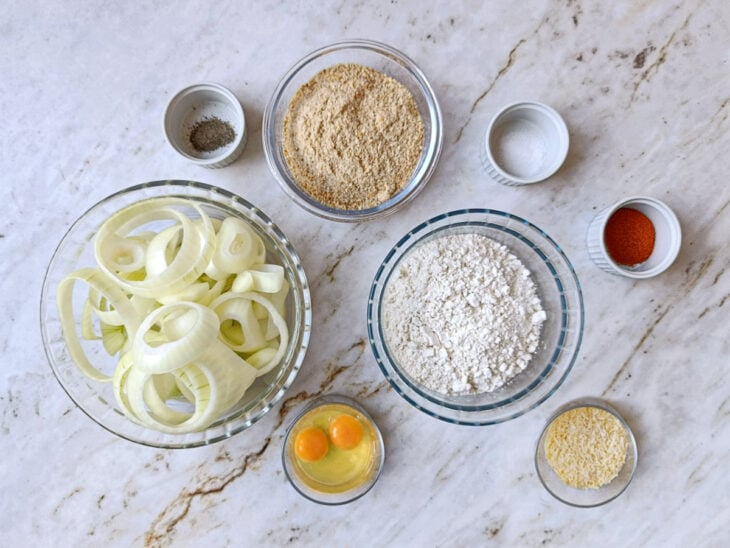 Ingredientes organizados sobre a bancada com cebolas, farinhas, ovo e temperos.