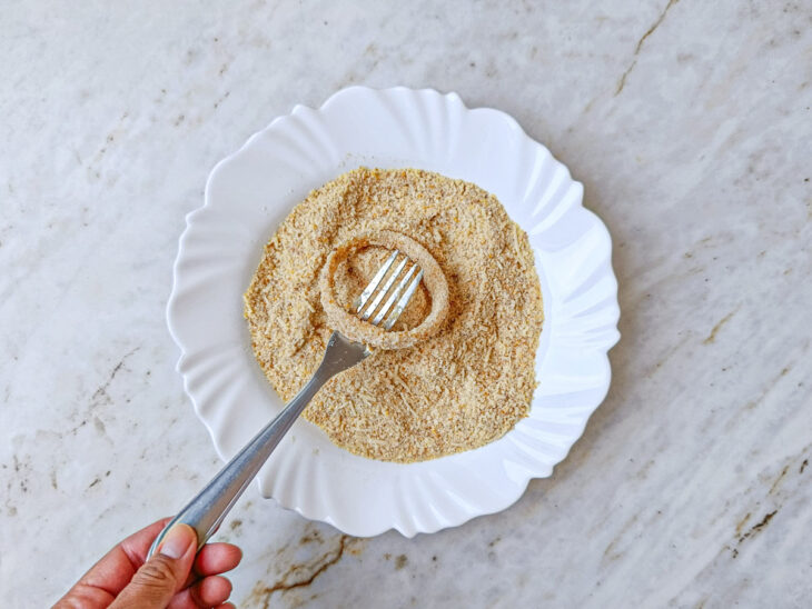 Anel de cebola recebendo uma segunda camada de ovo e farinha de rosca com parmesão.