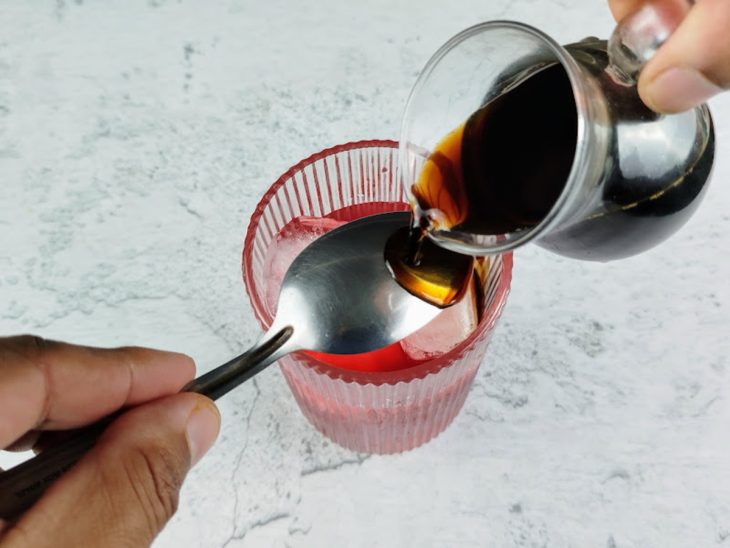 Café sendo adicionado ao copo com o auxílio de uma colher.