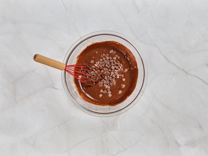 Massa do brownie em uma tigela misturada com gotas de chocolate.