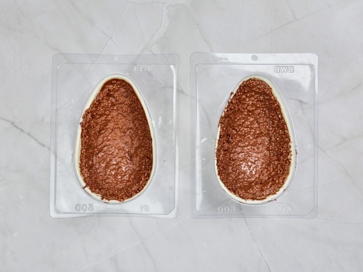 Forma com os ovos cobertos com uma camada de ganache e cereais.