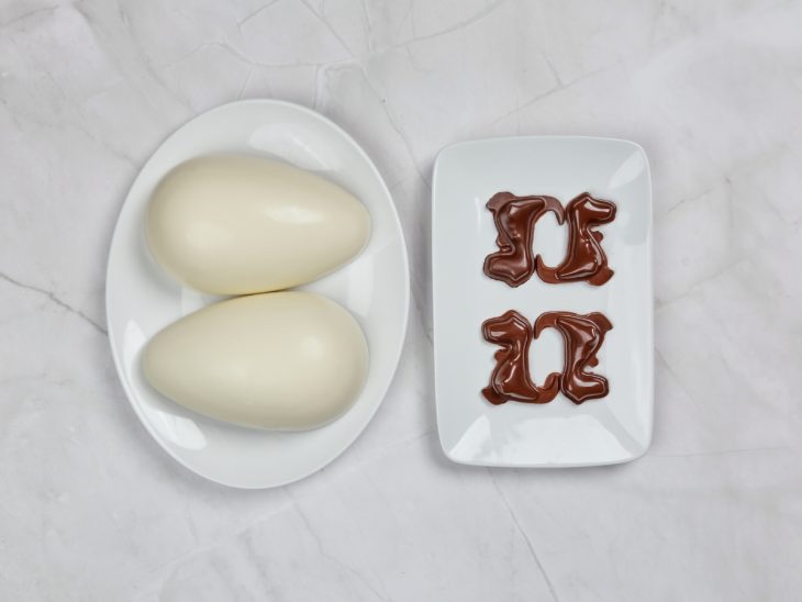Ovo e dinossauros de chocolate desenformados em pratos.