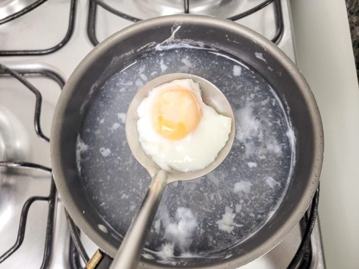 Uma panela contendo água fervendo com um ovo cozido.