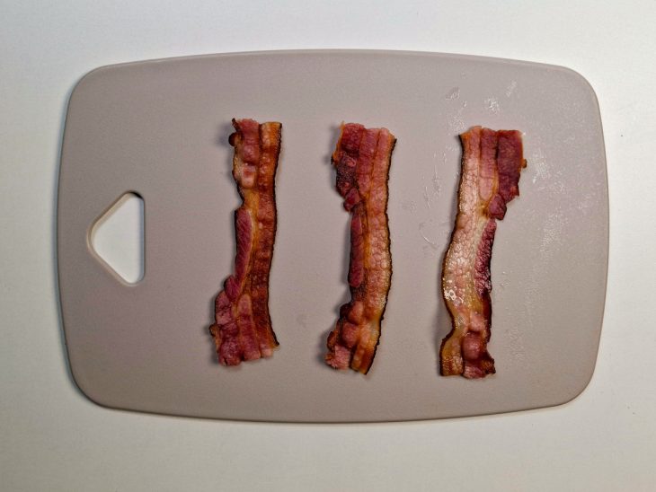 Tiras de bacon tostadas sobre uma tábua.
