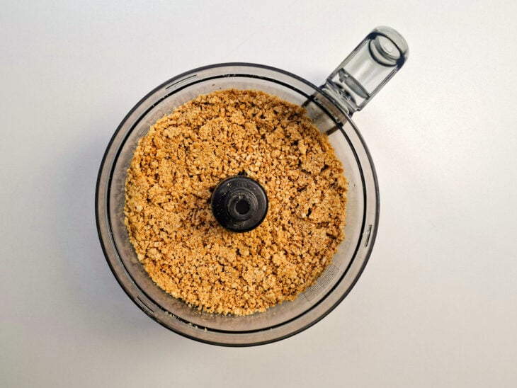 Amendoim torrado sendo colocado no copo do processador de alimentos.