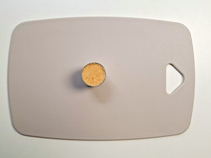 Dedos pressionando com força a mistura para dentro do aro até compactar completamente.