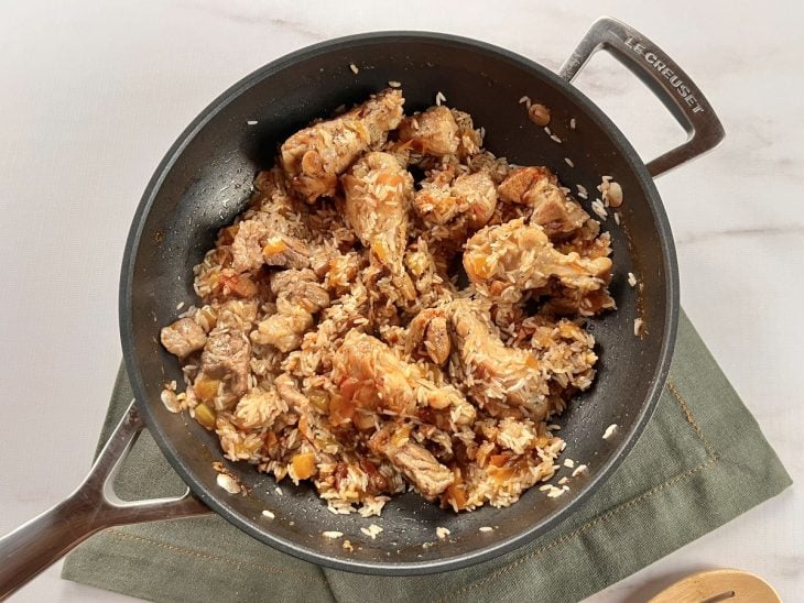 Arroz adicionado na panela com frango e outros ingredientes.