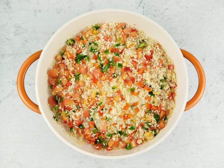 Pimentões, o tomate e o arroz adicionados na panela.