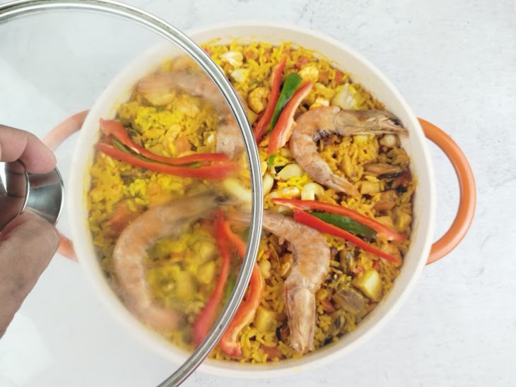 Camarões adicionados e panela sendo tampada.