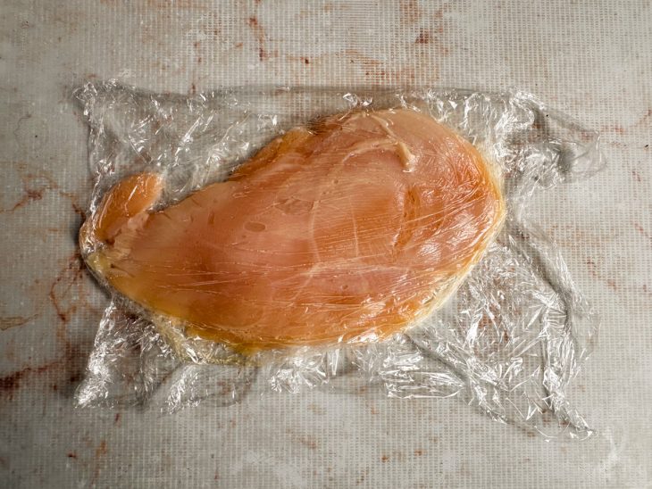 Frango sendo batido até ficar fino e uniforme.