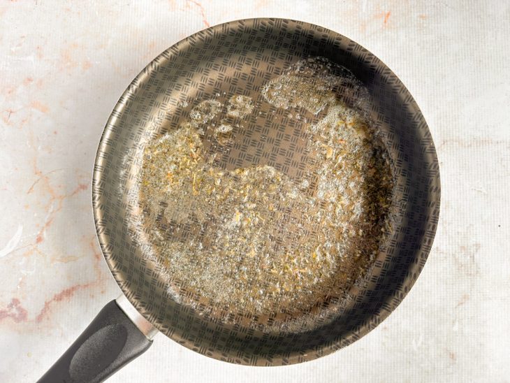 Manteiga derretendo na frigideira com ervas finas.