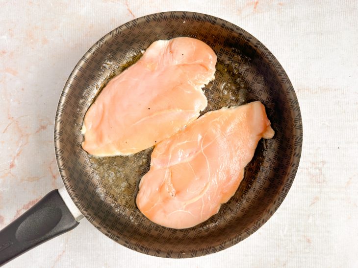Filés de frango selando na frigideira sem serem mexidos.