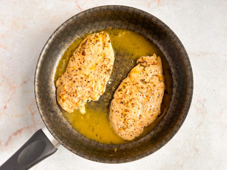 Frango dourado recebendo suco de laranja ao redor.