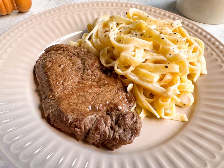 Prato montado com o paillard de mignon e o macarrão ao lado.