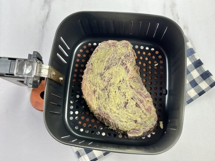 Uma cesta de airfryer contendo paleta bovina besuntada com manteiga.