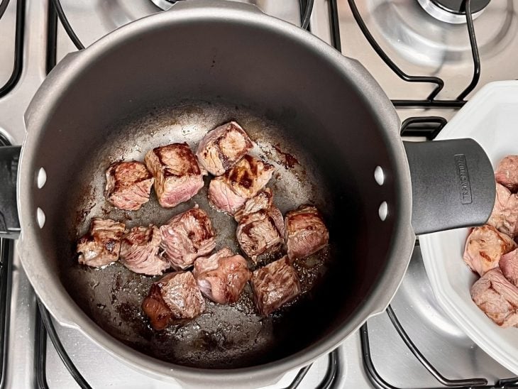 Uma panela de pressão com cubos de carne selados.