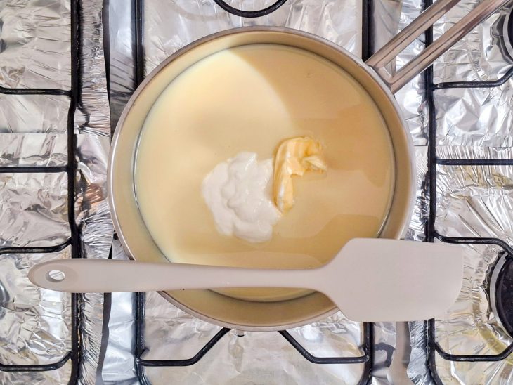 Leite condensado, manteiga e creme de leite sendo levados ao fogo em uma panela.